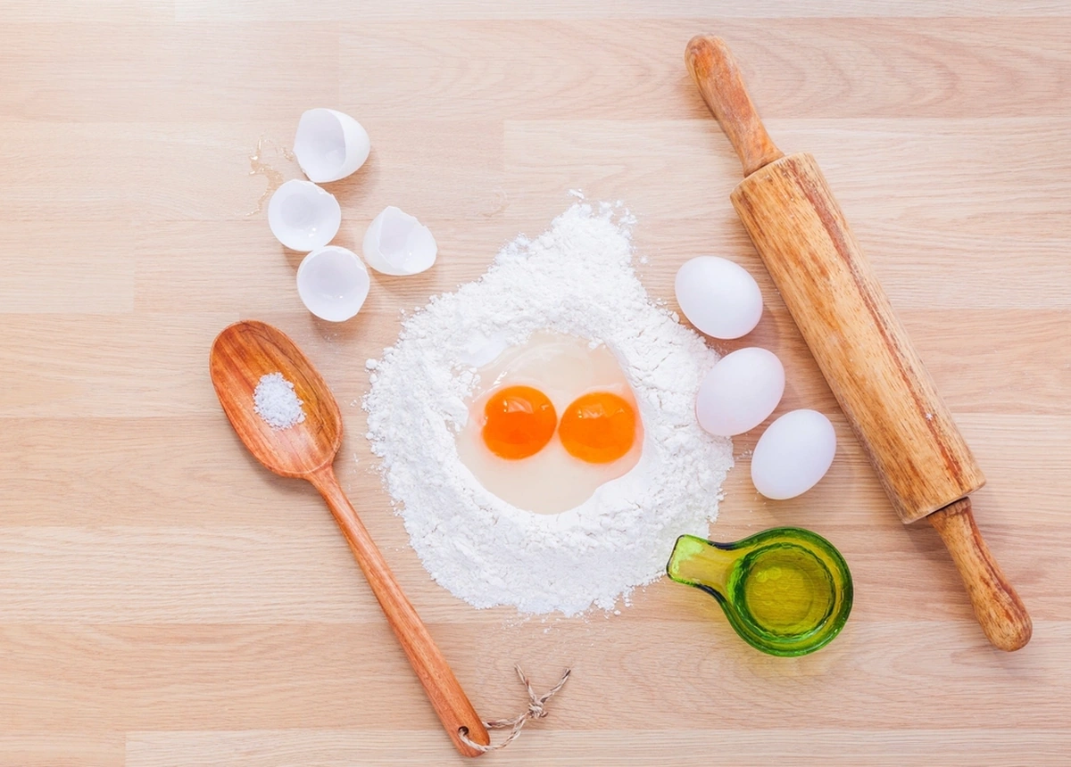 Ilustrasi tepung, telur dan rolling pin di meja dapur